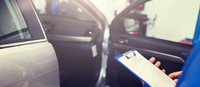 a picture of someone holding a document in front of a car with an open door